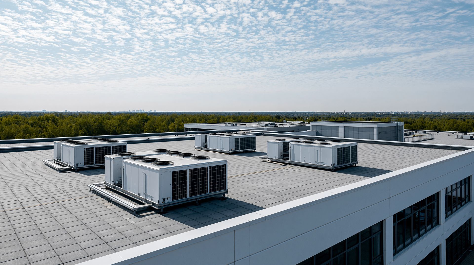 Unités de climatisation sur le toit d'un bâtiment commercial plat sous un ciel partiellement nuageux.