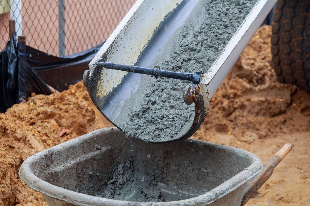 Cemento vertido desde un conducto a una carretilla en una obra en construcción.