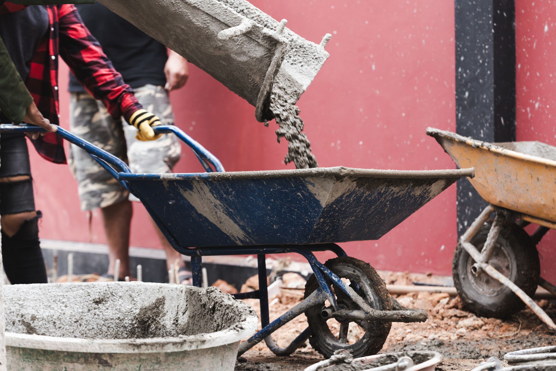 Trabajadores vierten hormigón en una carretilla en un sitio de construcción.
