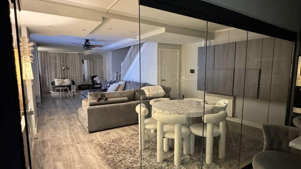 Sala de estar y comedor modernos de concepto abierto con sofá gris, mesa redonda y pisos de madera noble.