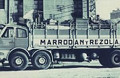 Una fotografía en blanco y negro de un camión estacionado frente a un edificio.