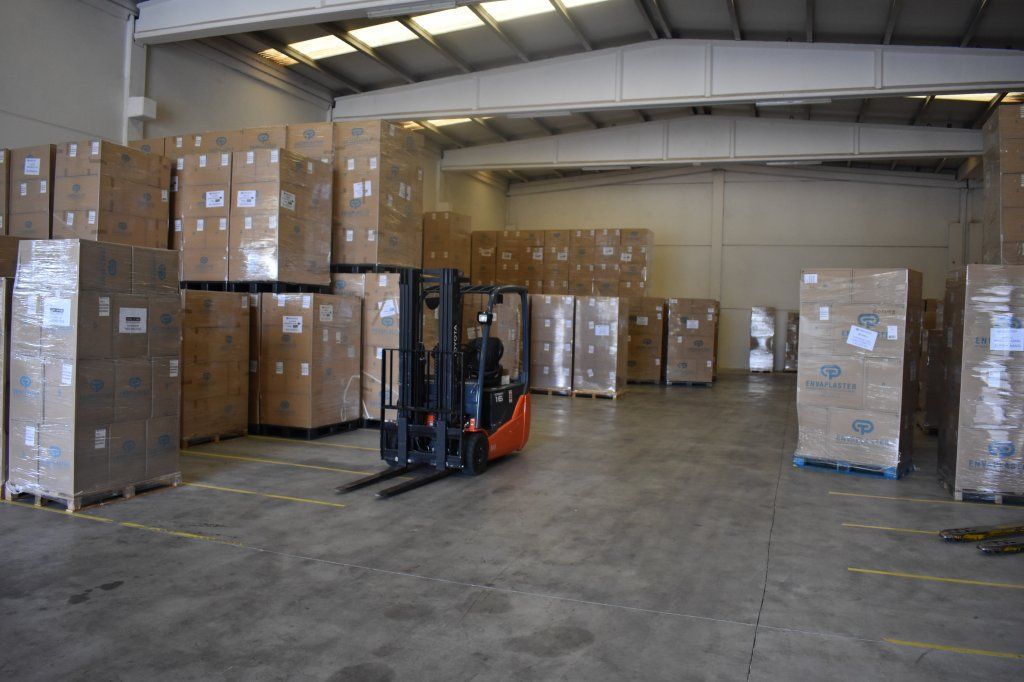 Una carretilla elevadora circula por un gran almacén lleno de cajas.