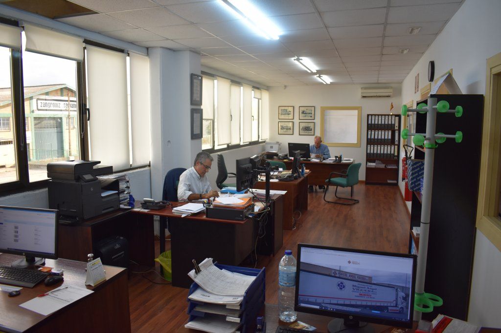 Un hombre está sentado en un escritorio en una oficina mirando una pantalla de computadora.