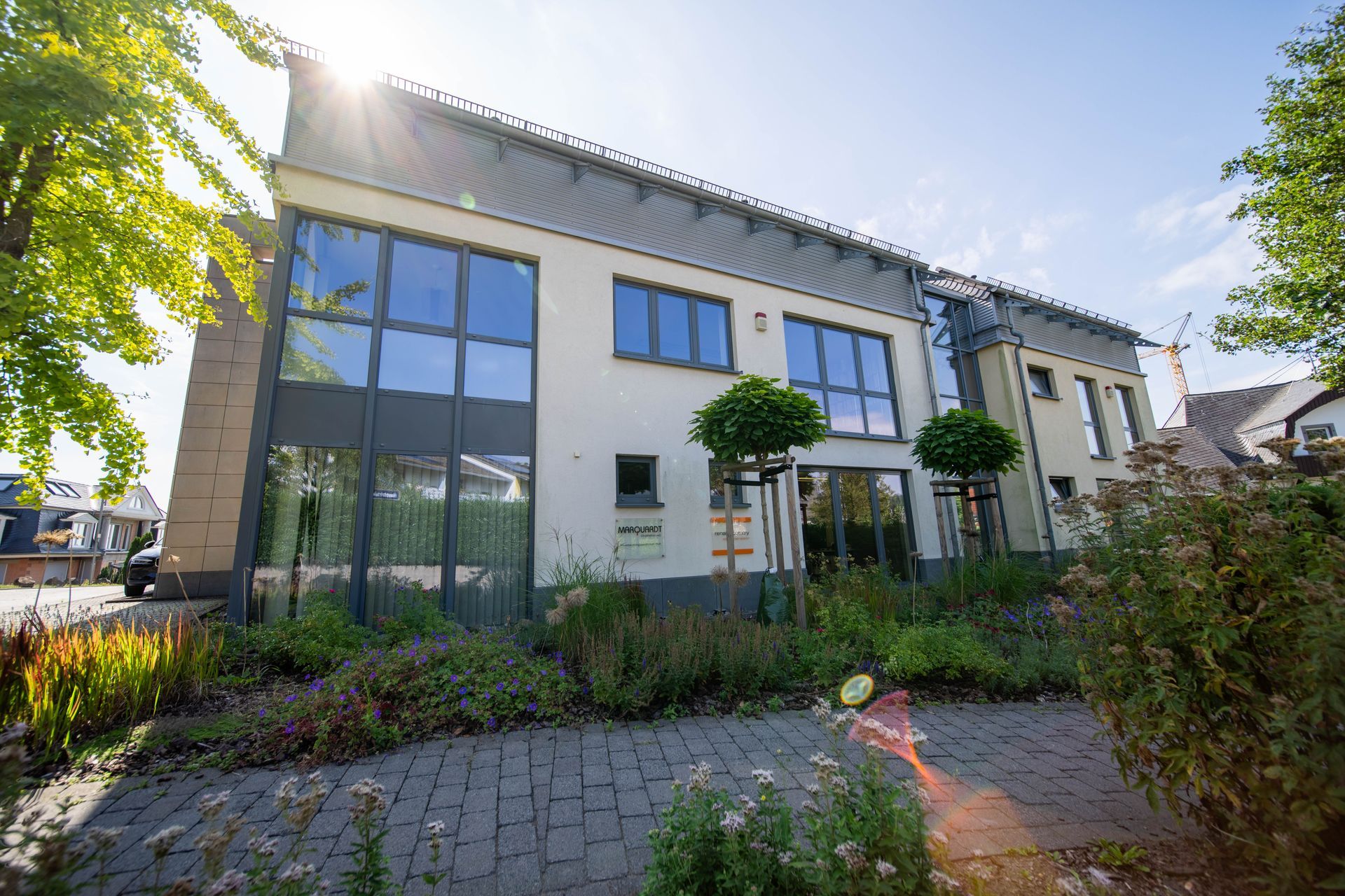 Fassade des Bürogebäudes mit großen Glasfronten und gepflegtem Grün.