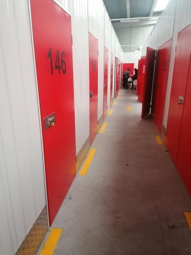 Un largo pasillo con puertas rojas y una línea amarilla en el suelo.