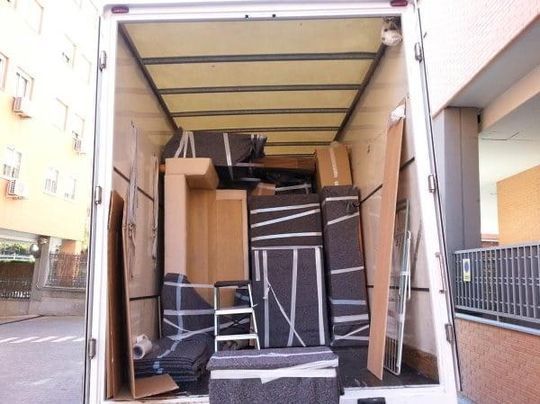 La parte trasera de un camión de mudanzas lleno de muebles y cajas.