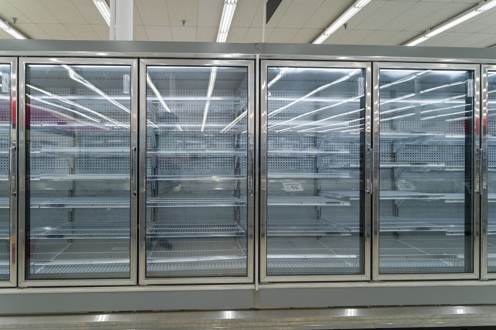Vitrines réfrigérées à portes vitrées vides dans une allée de supermarché
