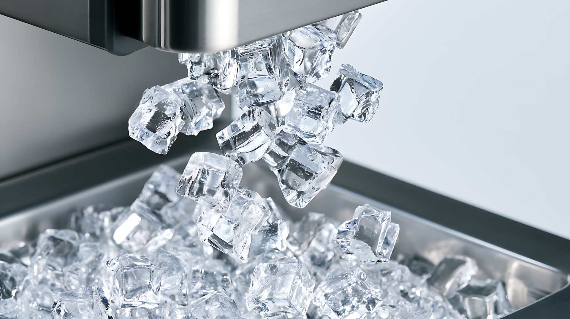 Des glaçons tombent d'une machine à glaçons en acier inoxydable dans un bac.