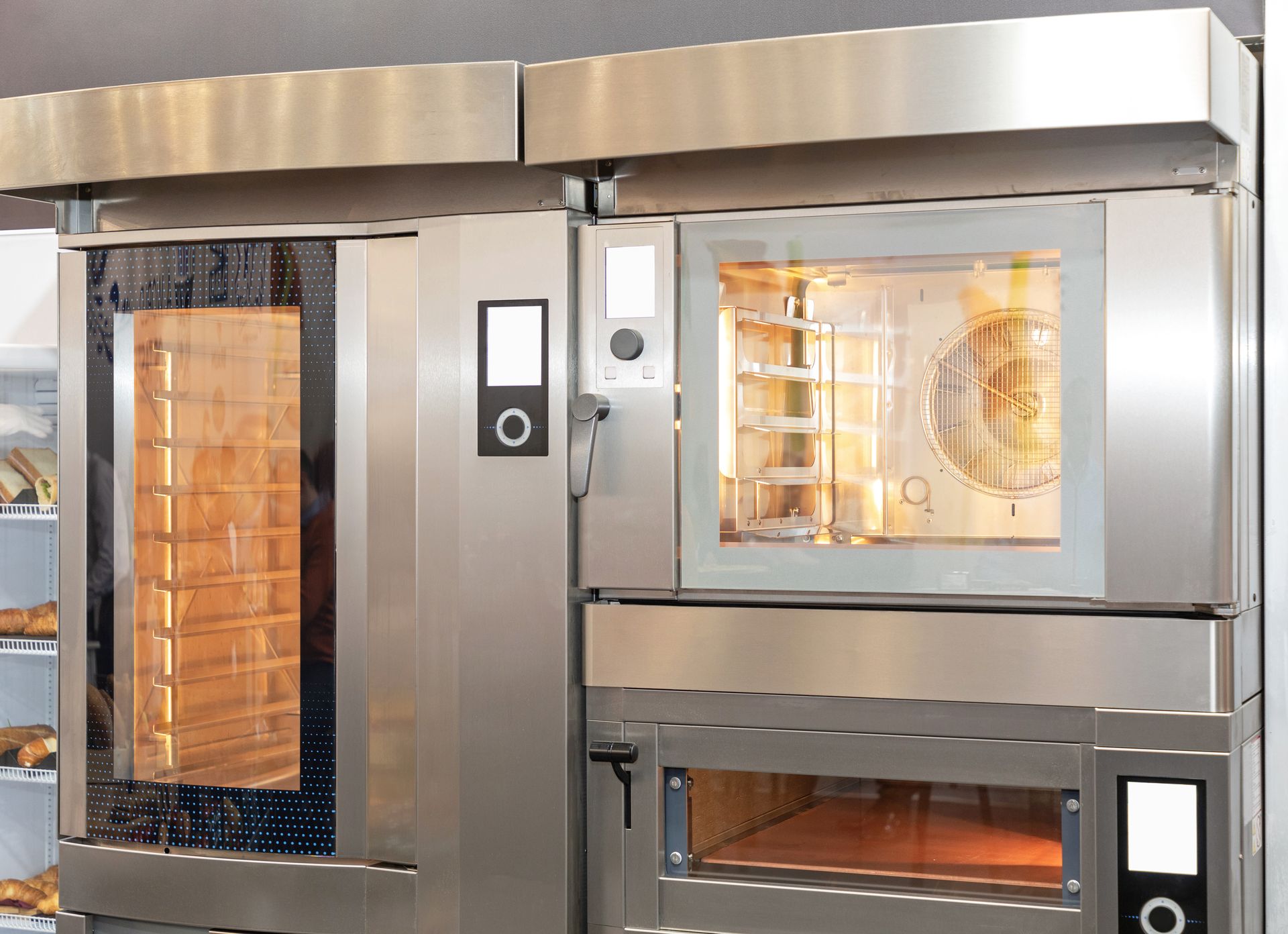 Fours commerciaux en acier inoxydable avec grilles intérieures éclairées dans une cuisine de boulangerie