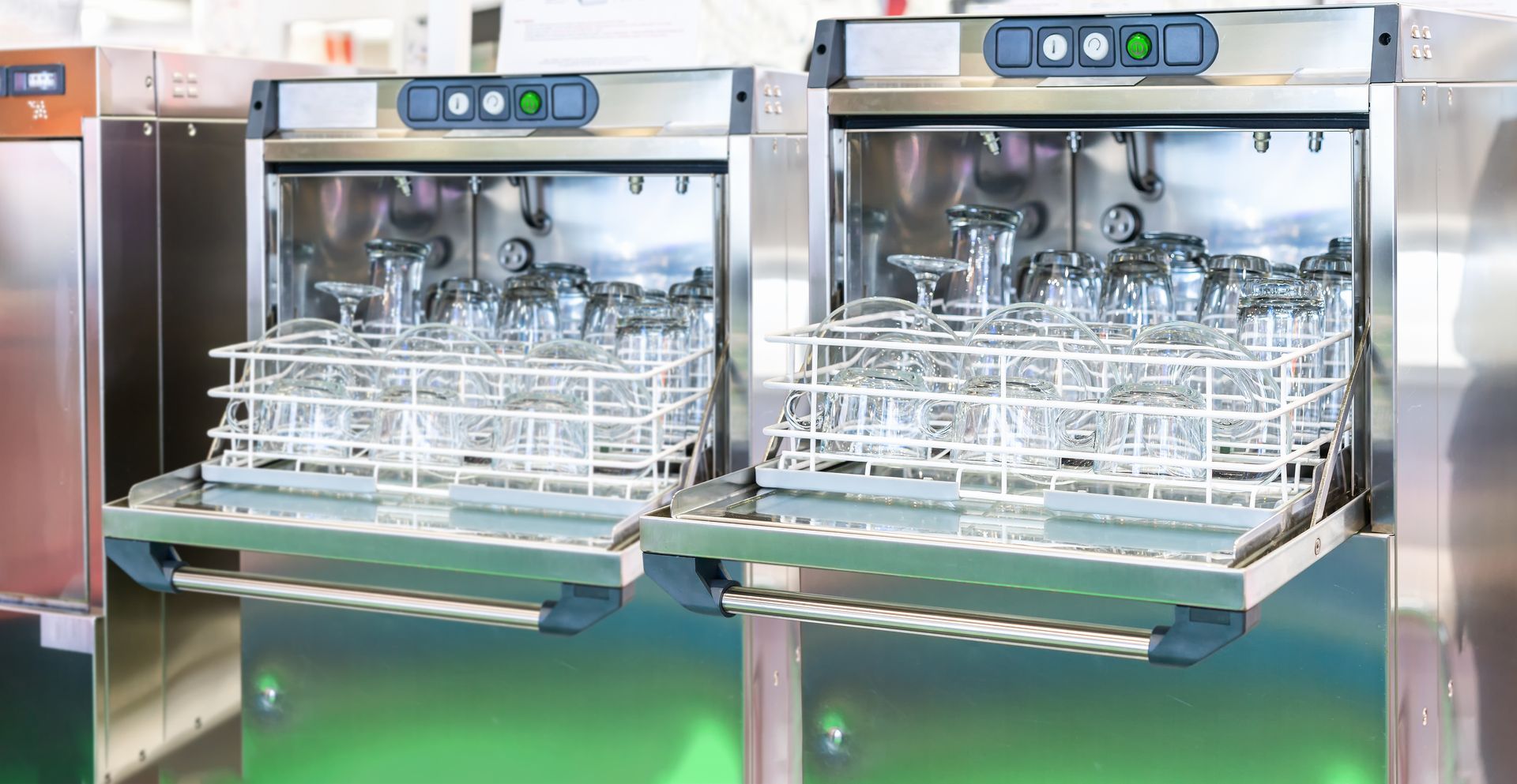 Deux lave-vaisselle commerciaux en acier inoxydable avec des paniers de verres propres dans une cuisine lumineuse