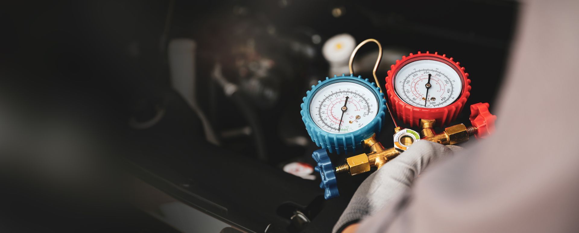 Manomètres de climatisation automatique avec cadrans bleus et rouges utilisés dans le compartiment moteur d'un véhicule