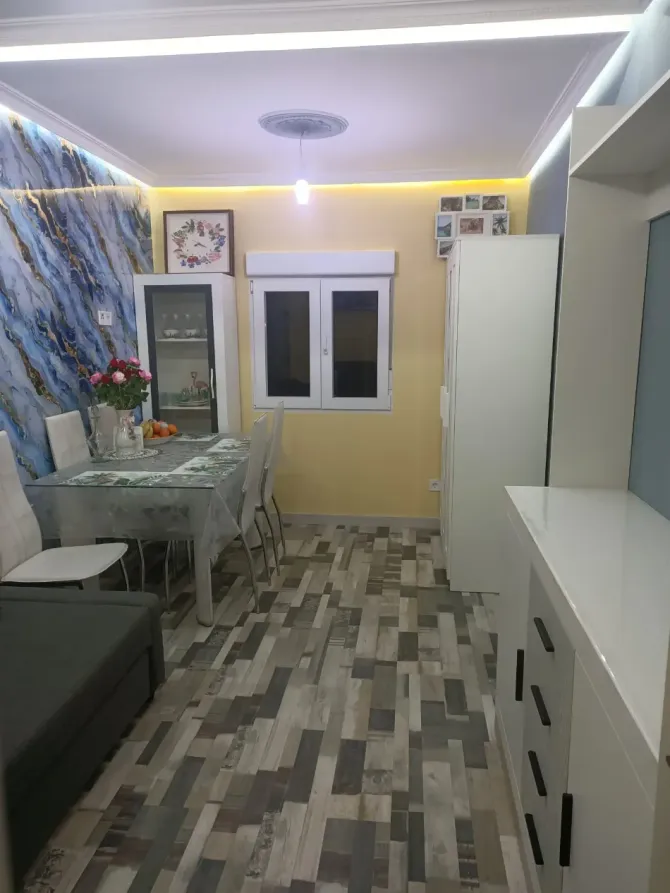 Baño compacto con ducha de cristal, inodoro blanco y paredes con diseño de mármol.
