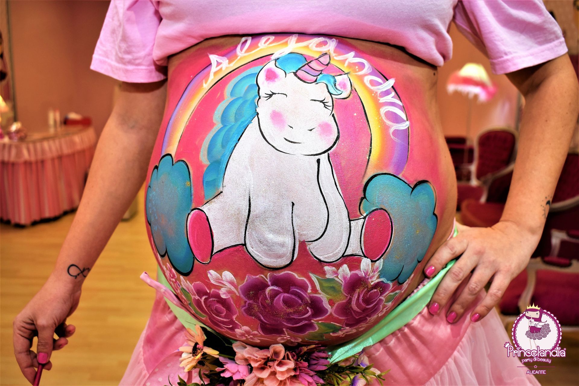 Una mujer embarazada tiene un unicornio pintado en su vientre.