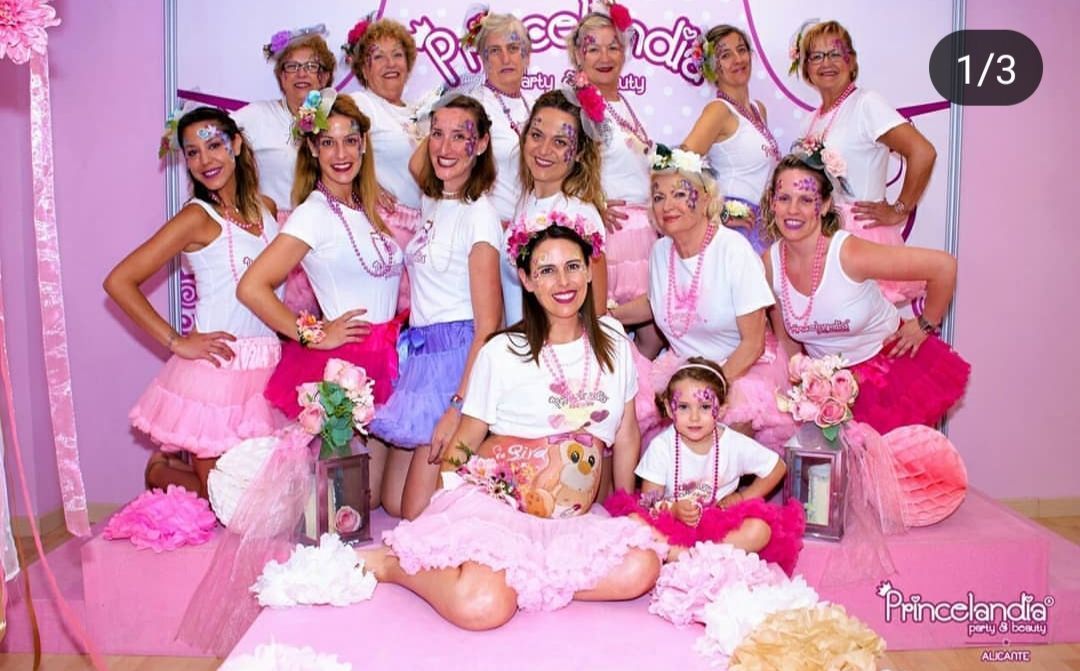 Un grupo de mujeres posa para una fotografía en una habitación rosa.