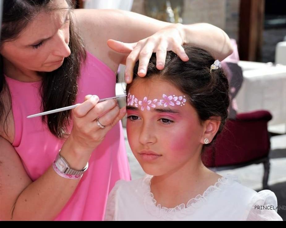 Una mujer está aplicando maquillaje en la cara de una niña.