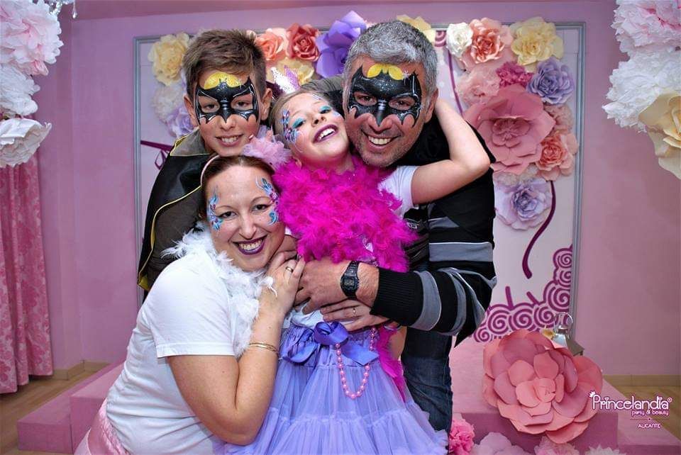 Una familia posa para una foto frente a una pared de flores.