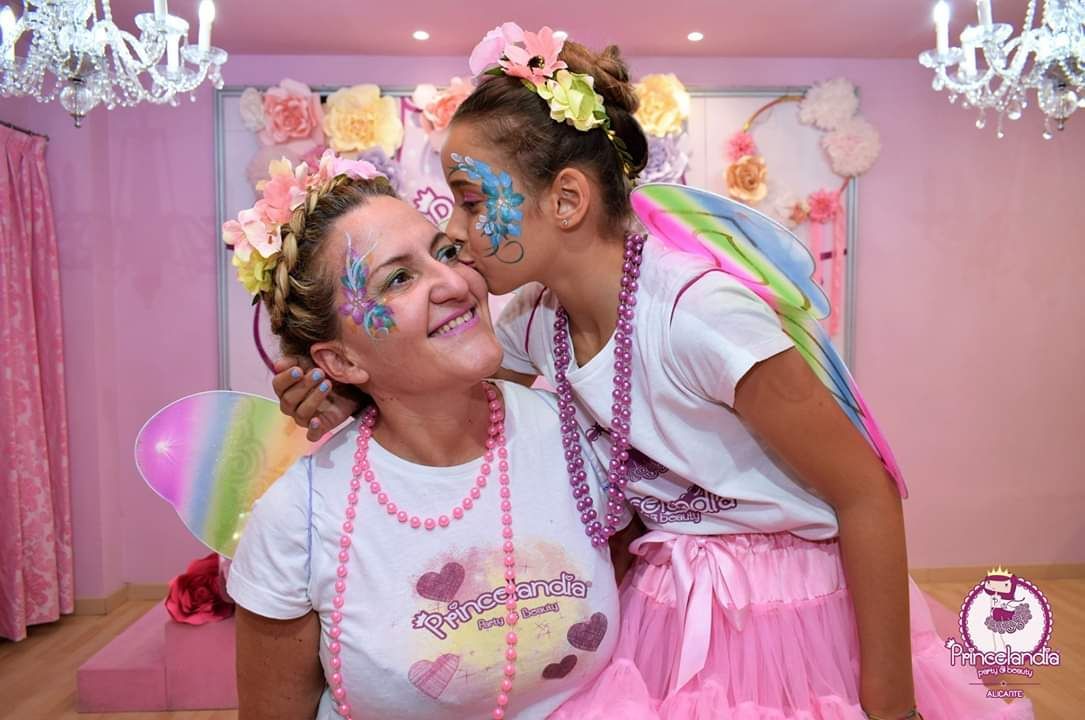 Una mujer y una niña están paradas una al lado de la otra en una habitación rosa.