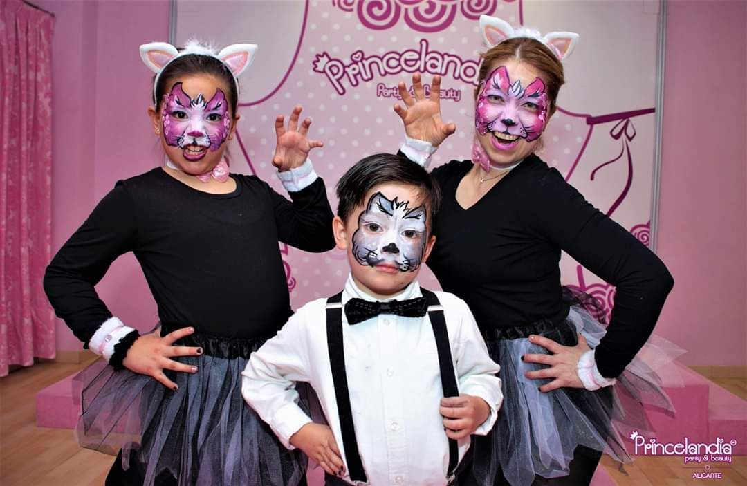 Dos niñas y un niño con pintura facial de gato en sus caras.