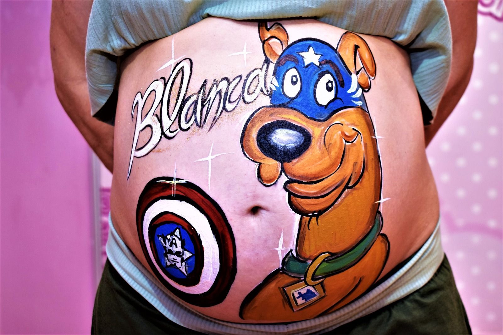 Una mujer embarazada tiene Scooby Doo pintado en su vientre.