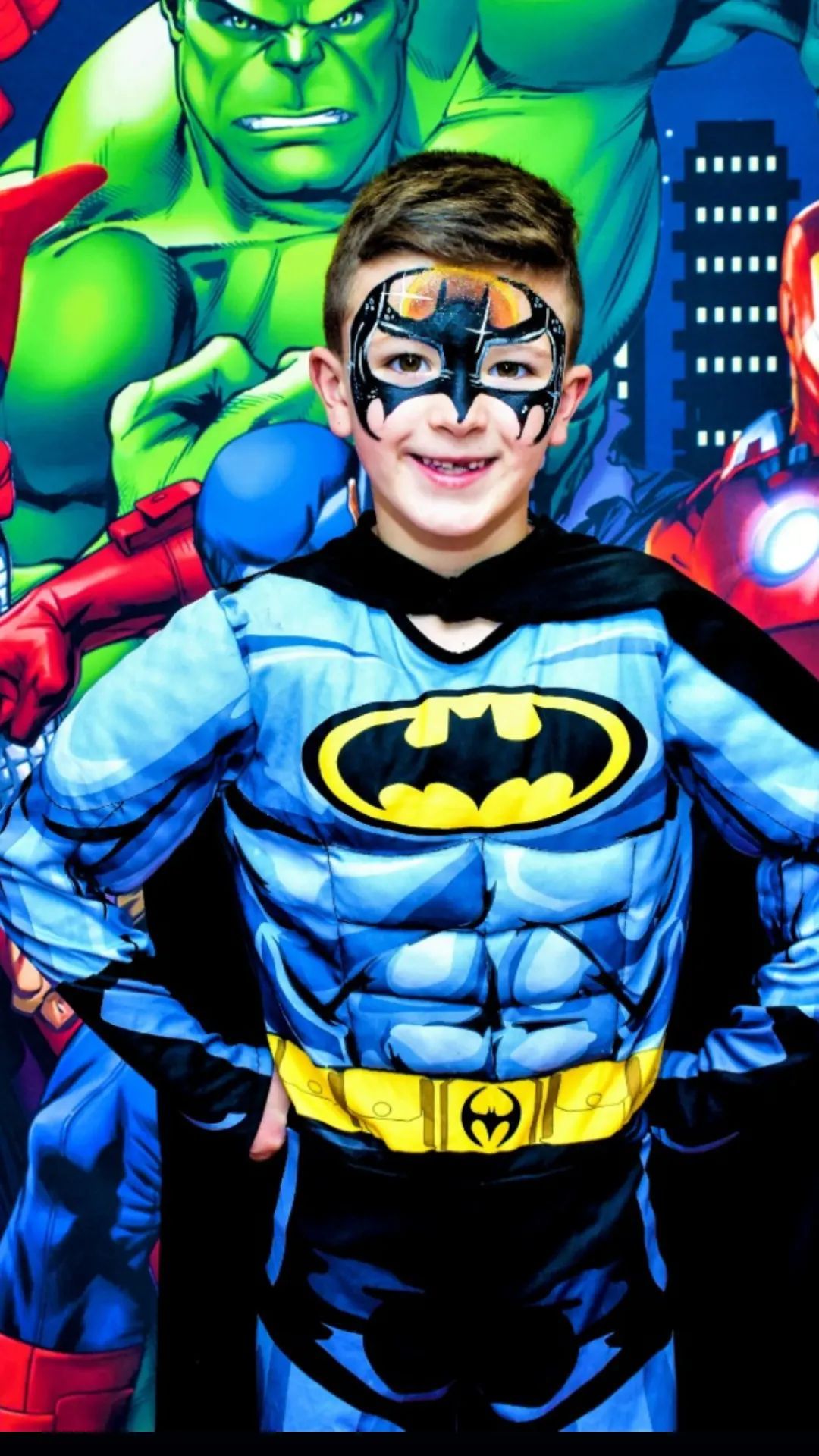 Un niño pequeño con un disfraz de Batman posa para una fotografía.