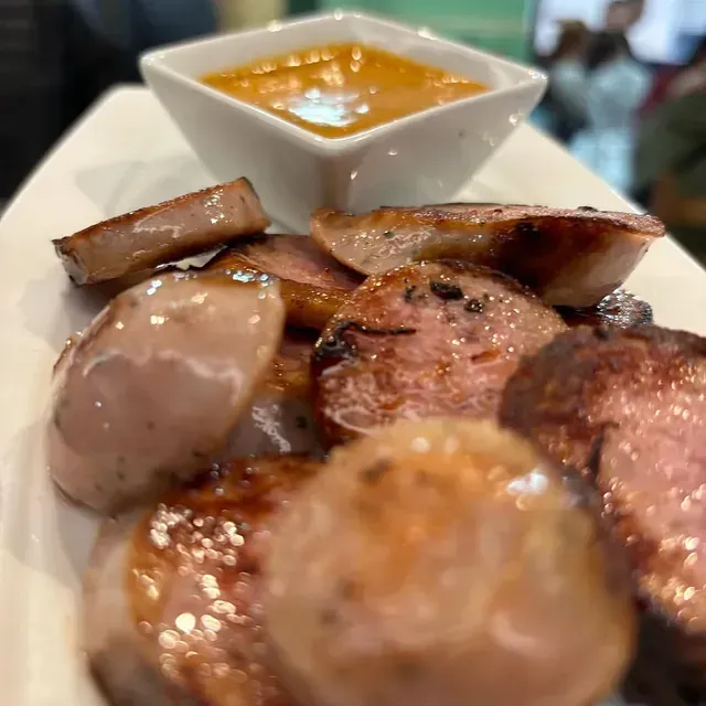 Un plato blanco cubierto con carne y un tazón de salsa.