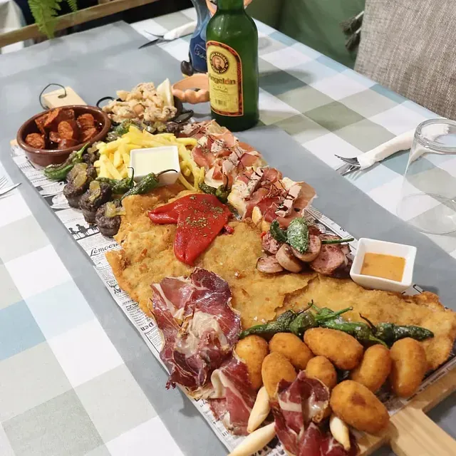 Una larga bandeja de comida con una botella de cerveza en la mesa.