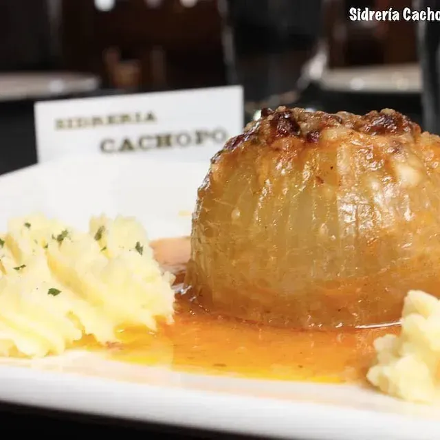 Un plato blanco cubierto con puré de patatas y una cebolla rellena.