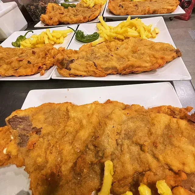 Una mesa cubierta con platos de comida frita y papas fritas.