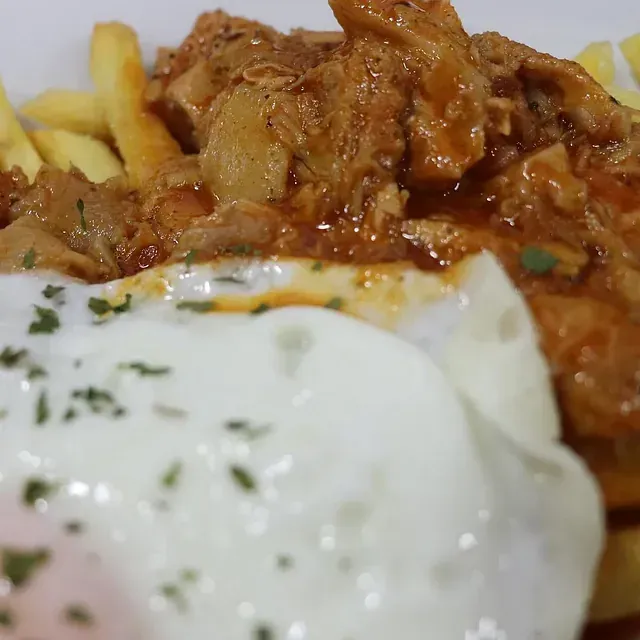 Un primer plano de un plato de comida con papas fritas y un huevo escalfado.
