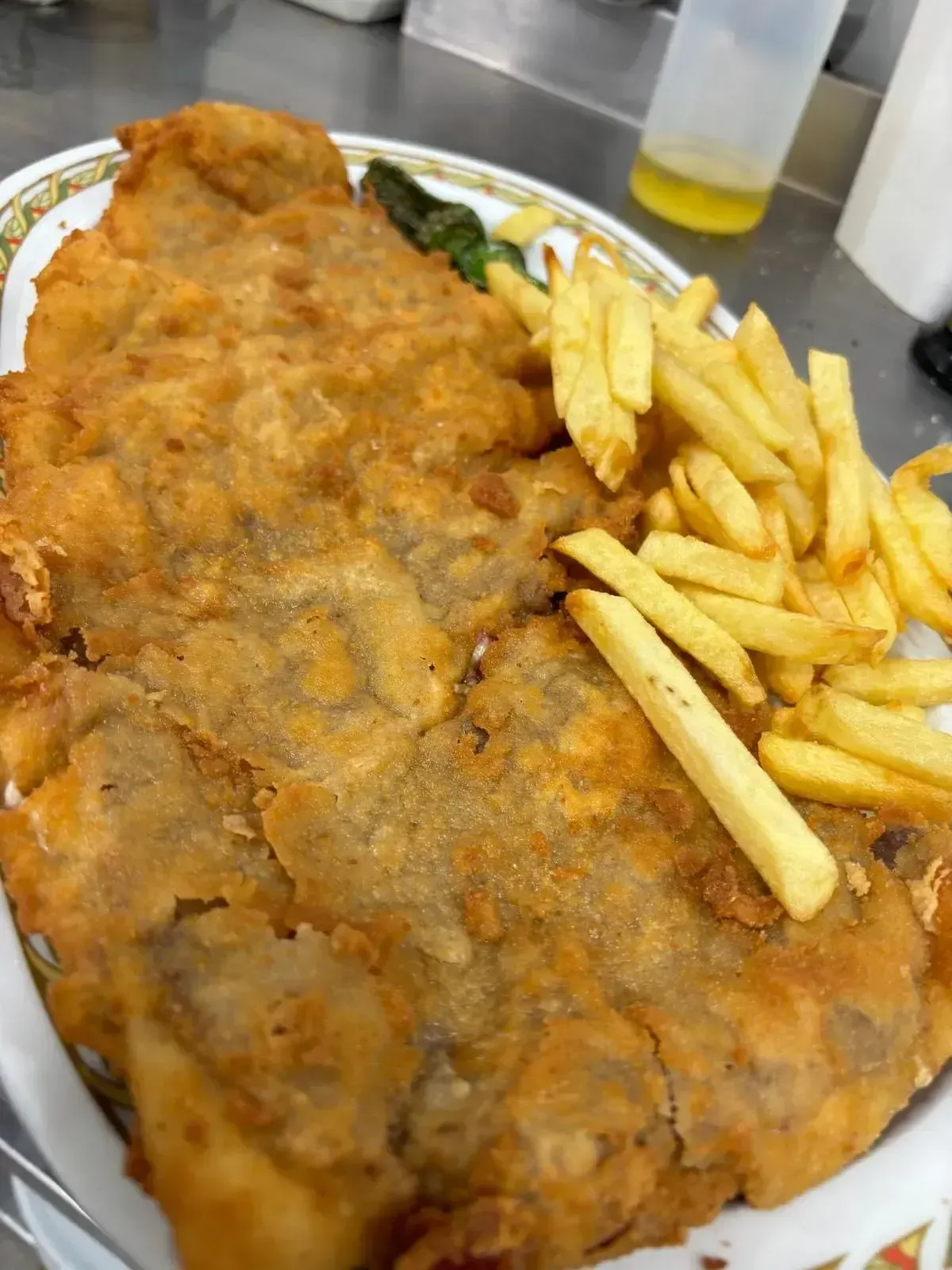 Escalope empanado y frito con patatas fritas en un plato blanco en un restaurante.