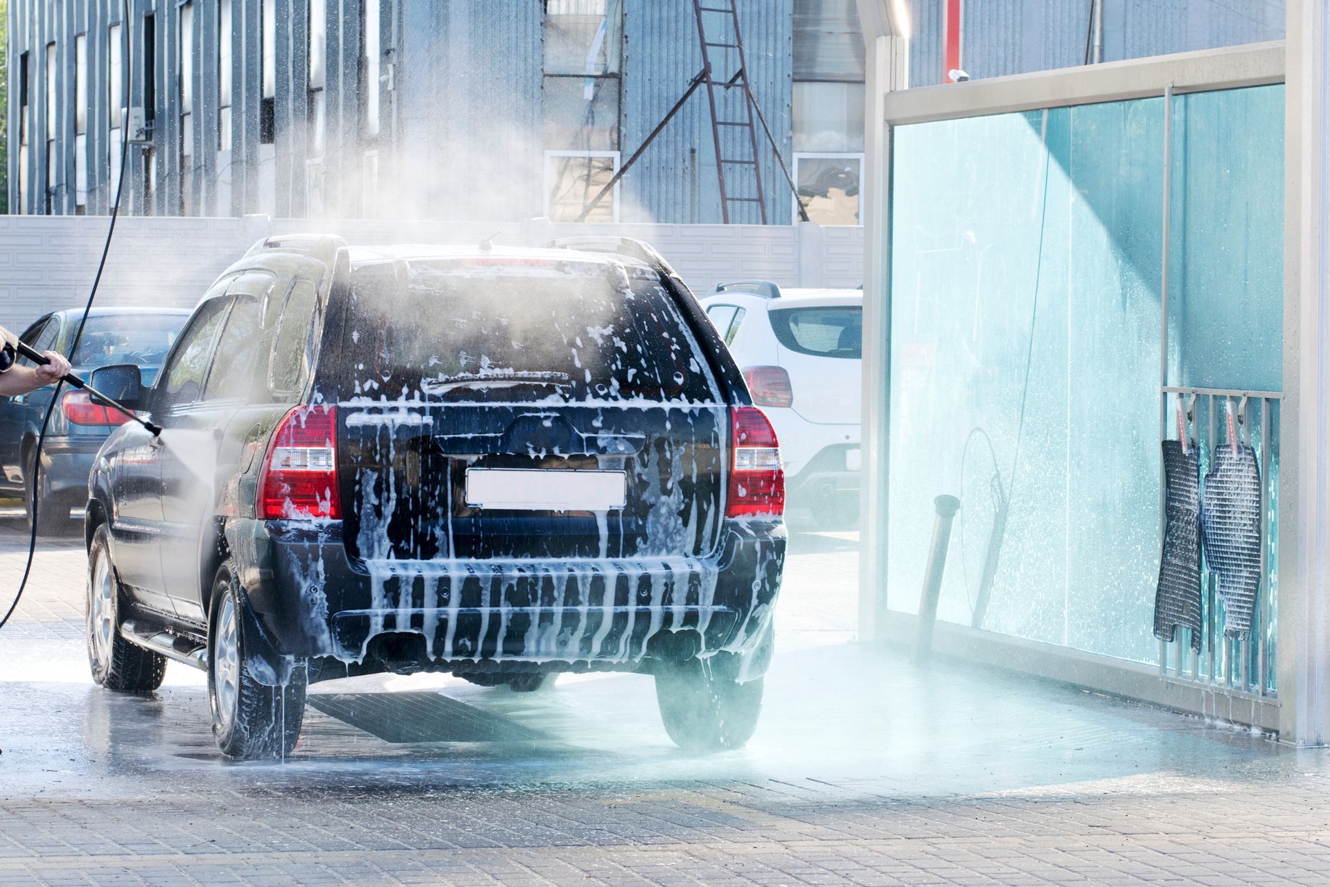 Voiture noire lavée à l'eau savonneuse dans un lave-auto.