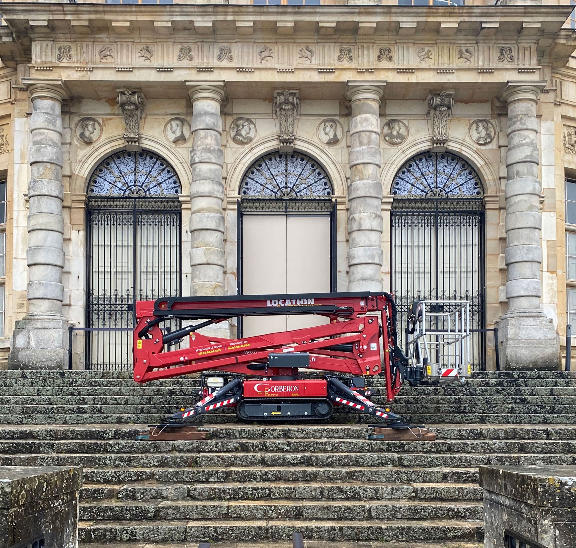 Nacelle-araignée non déployée posée sur le double escalier d'un grand bâtiment