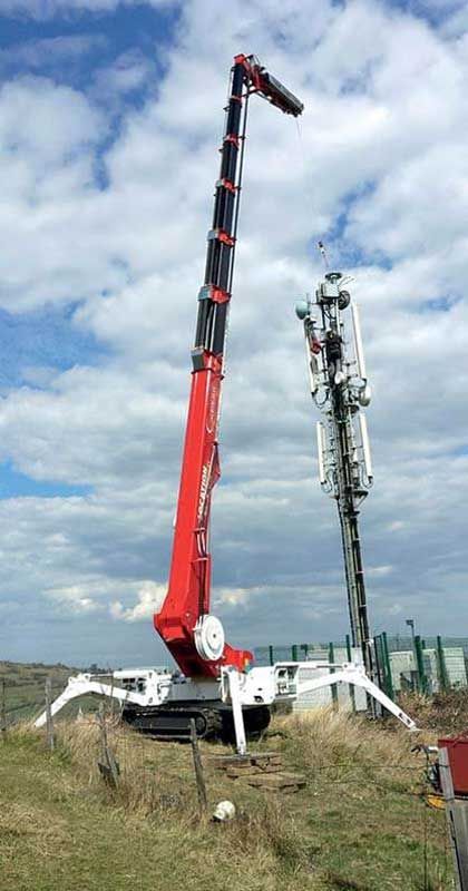 Grue sur chenilles déployée à côté d'une antenne