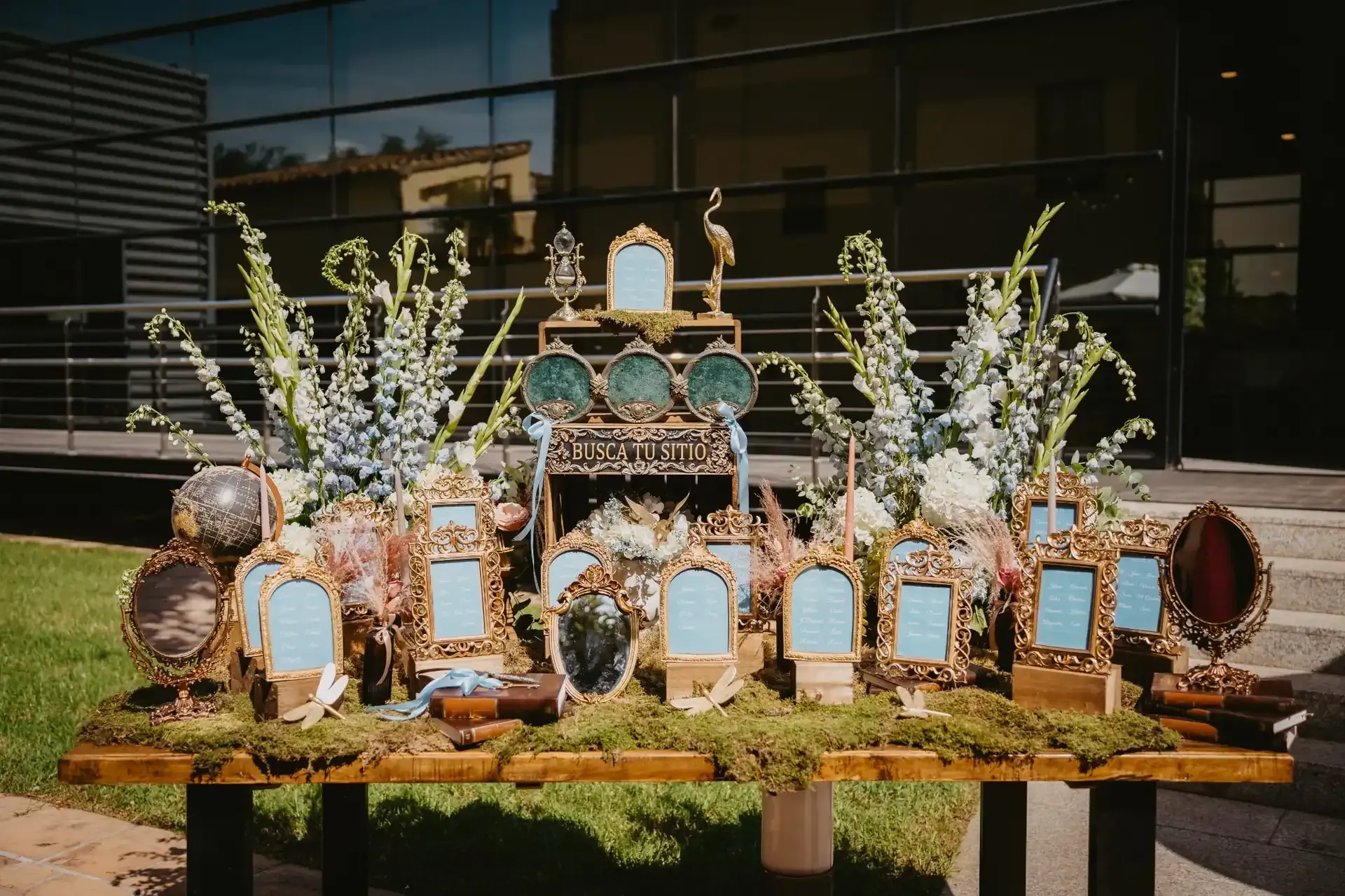 Exhibición de mesa con marcos dorados ornamentados, espejos y arreglos florales.