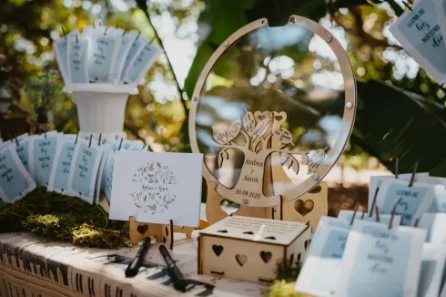 Decoración de boda con árbol de madera, caja de registro y recuerdos para los invitados sobre una mesa cubierta de musgo.