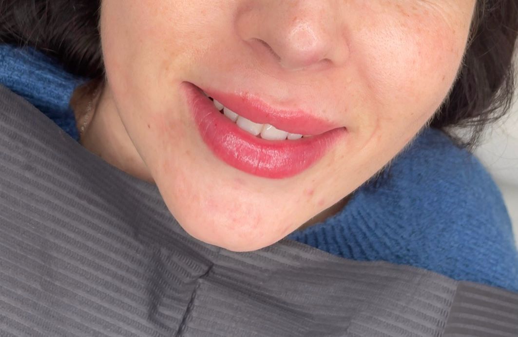 Un primer plano del rostro de una mujer con lápiz labial rojo en los labios.
