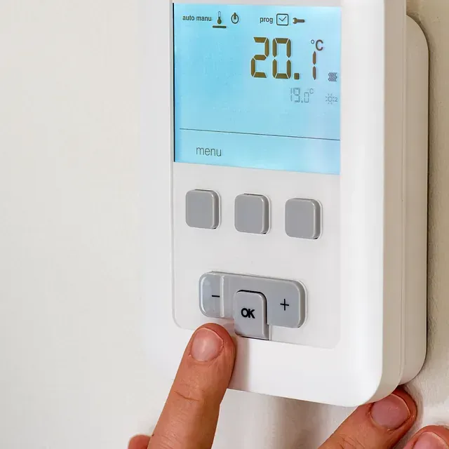 Una persona está presionando el botón Aceptar en un termostato.