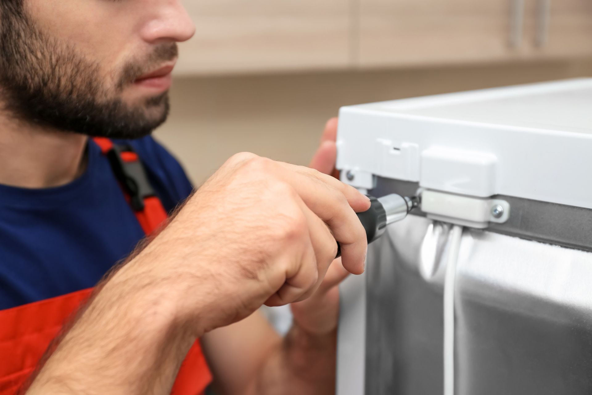 Un hombre está arreglando un refrigerador con un destornillador.