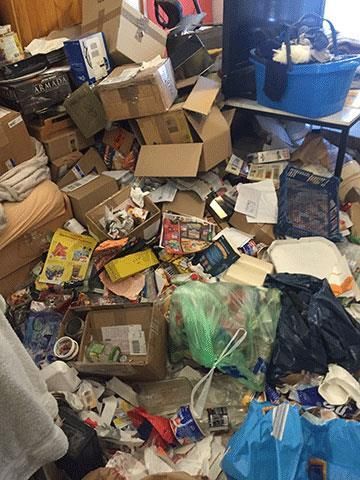 Der Raum ist voller Gerümpel: Pappkartons, Müllsäcke, Lebensmittelbehälter und sonstiger Schutt.