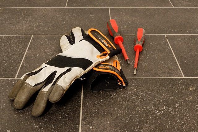 Gants de travail et tournevis rouges sur un sol carrelé
