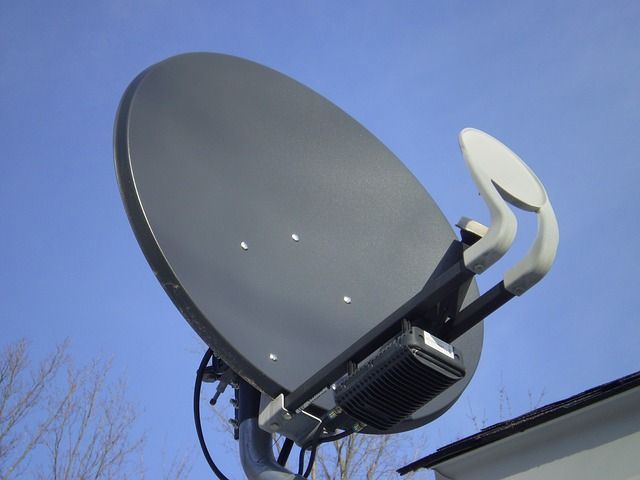 Grande antenne parabolique grise installée à l'extérieur sur fond de ciel bleu