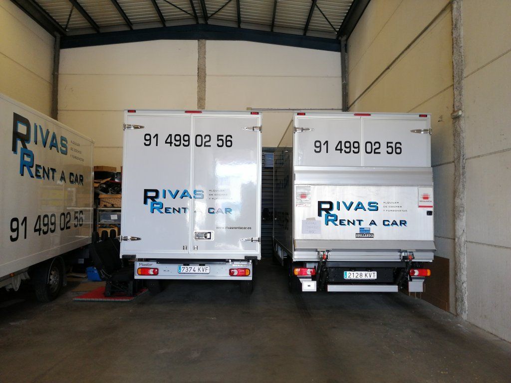 Dos camiones de Rivas Rent a Car están estacionados en un almacén.