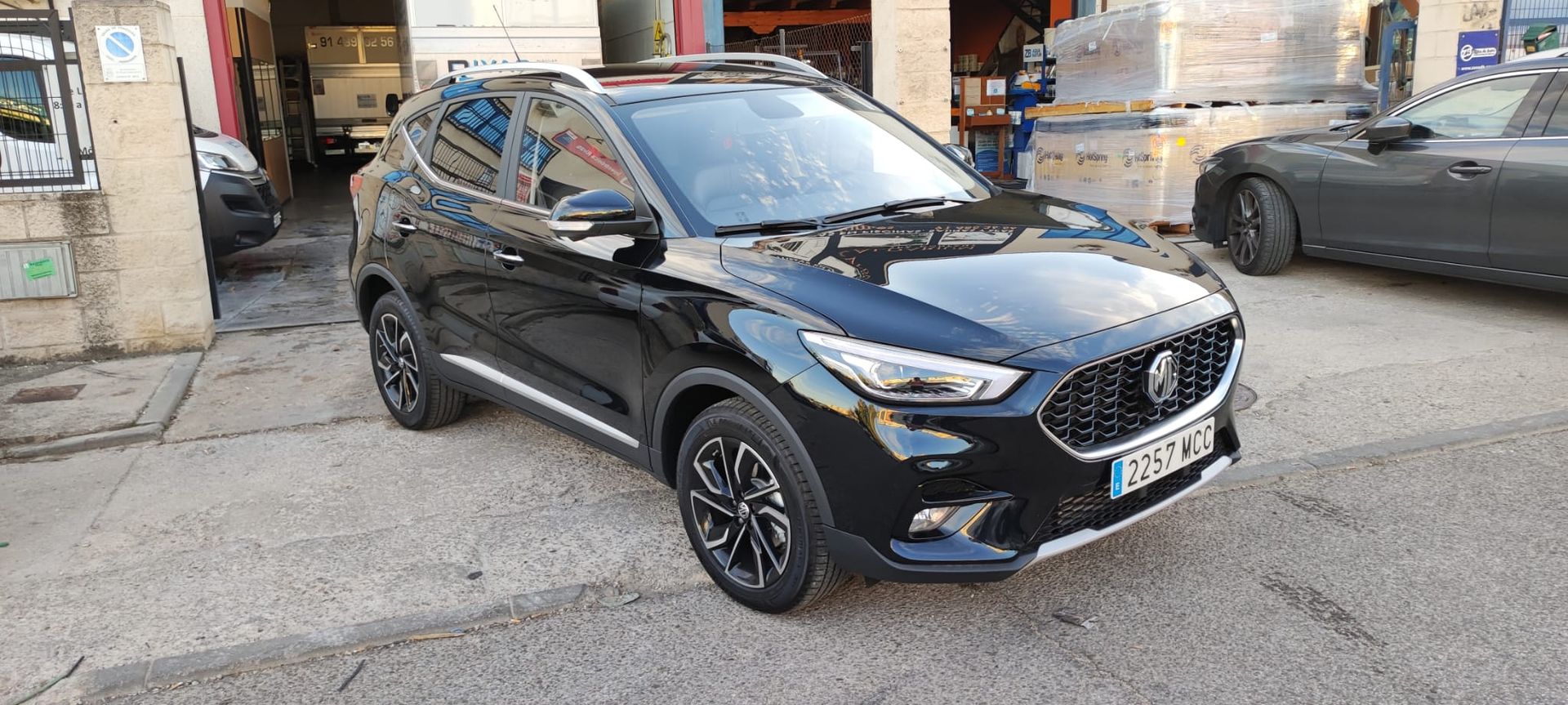 Un coche negro está aparcado delante de un edificio.