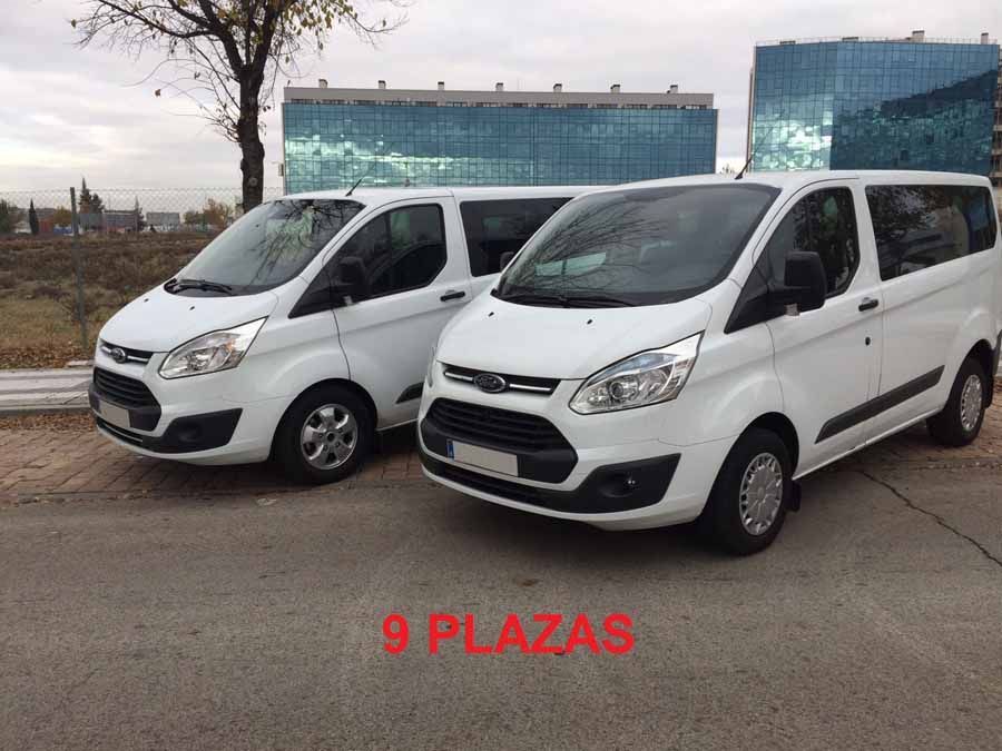 Dos furgonetas blancas están estacionadas una al lado de la otra al costado de la carretera.