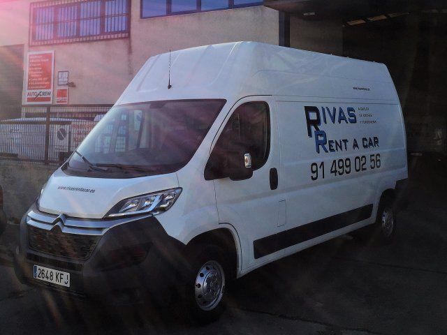 Dos camionetas blancas estacionadas frente a un edificio que dice Rivas