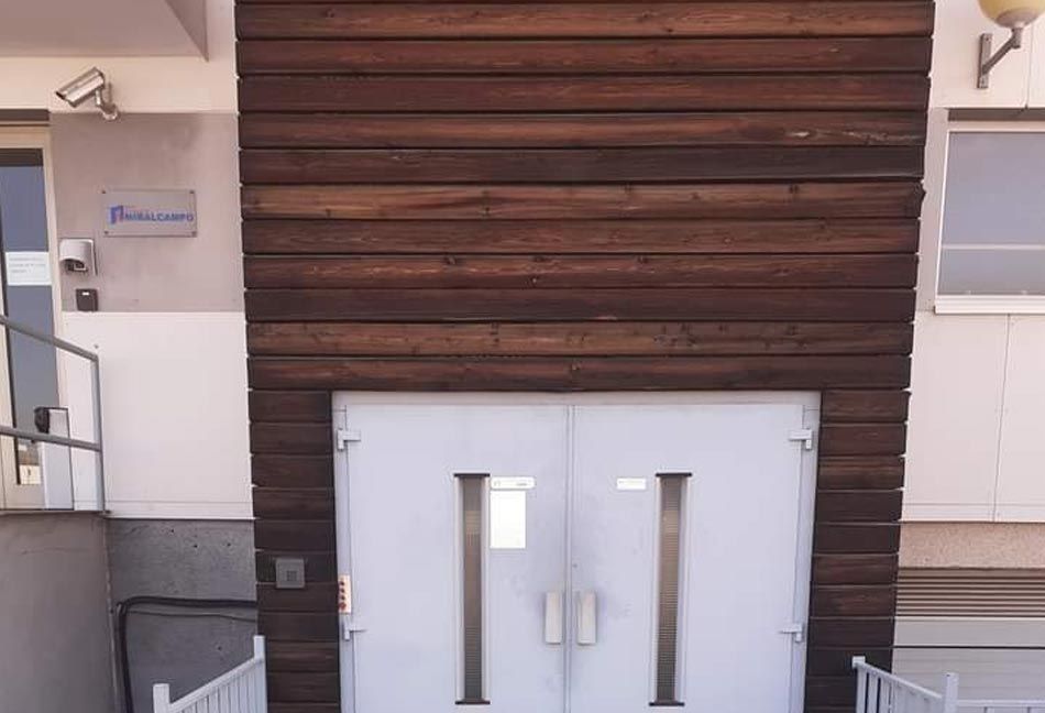 Un edificio con revestimiento de madera y una puerta blanca.