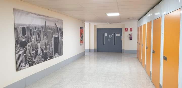 Un largo pasillo con puertas naranjas y un gran cuadro en la pared.