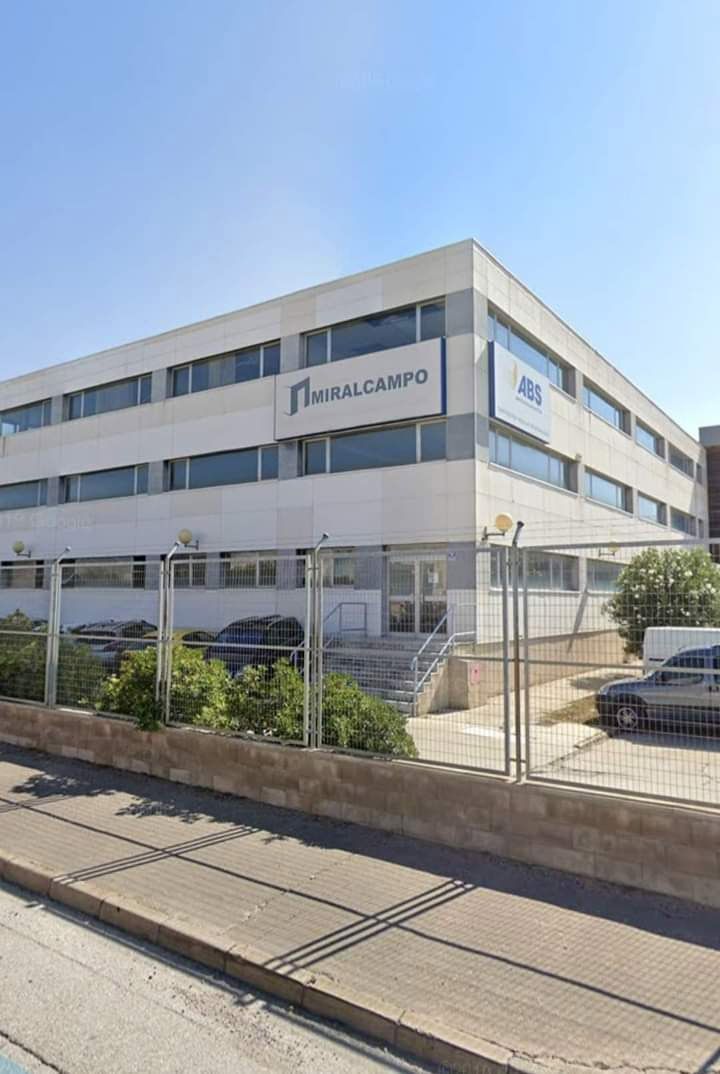 Un gran edificio blanco con coches aparcados delante.