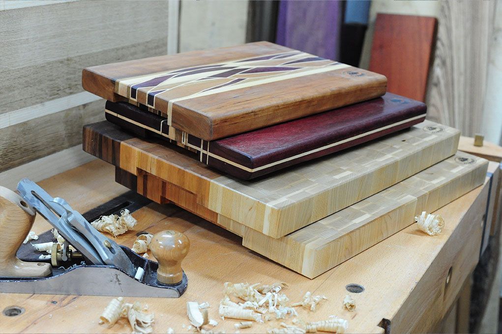 Auf einem Holztisch sind drei Holzschneidebretter übereinander gestapelt.