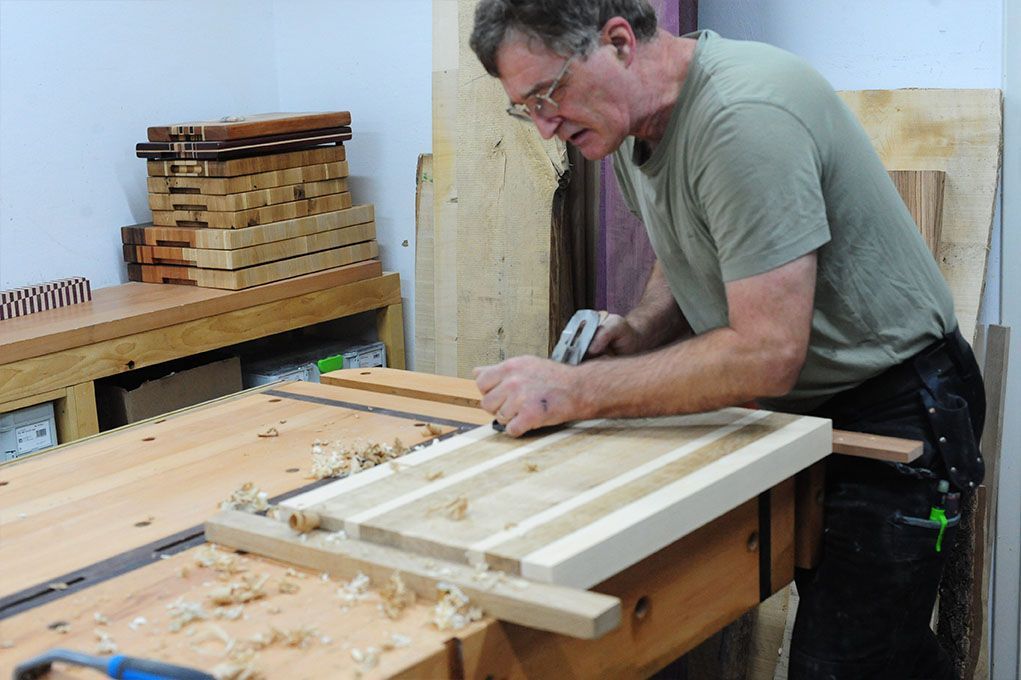 Ein Mann bearbeitet ein Stück Holz auf einer Werkbank.